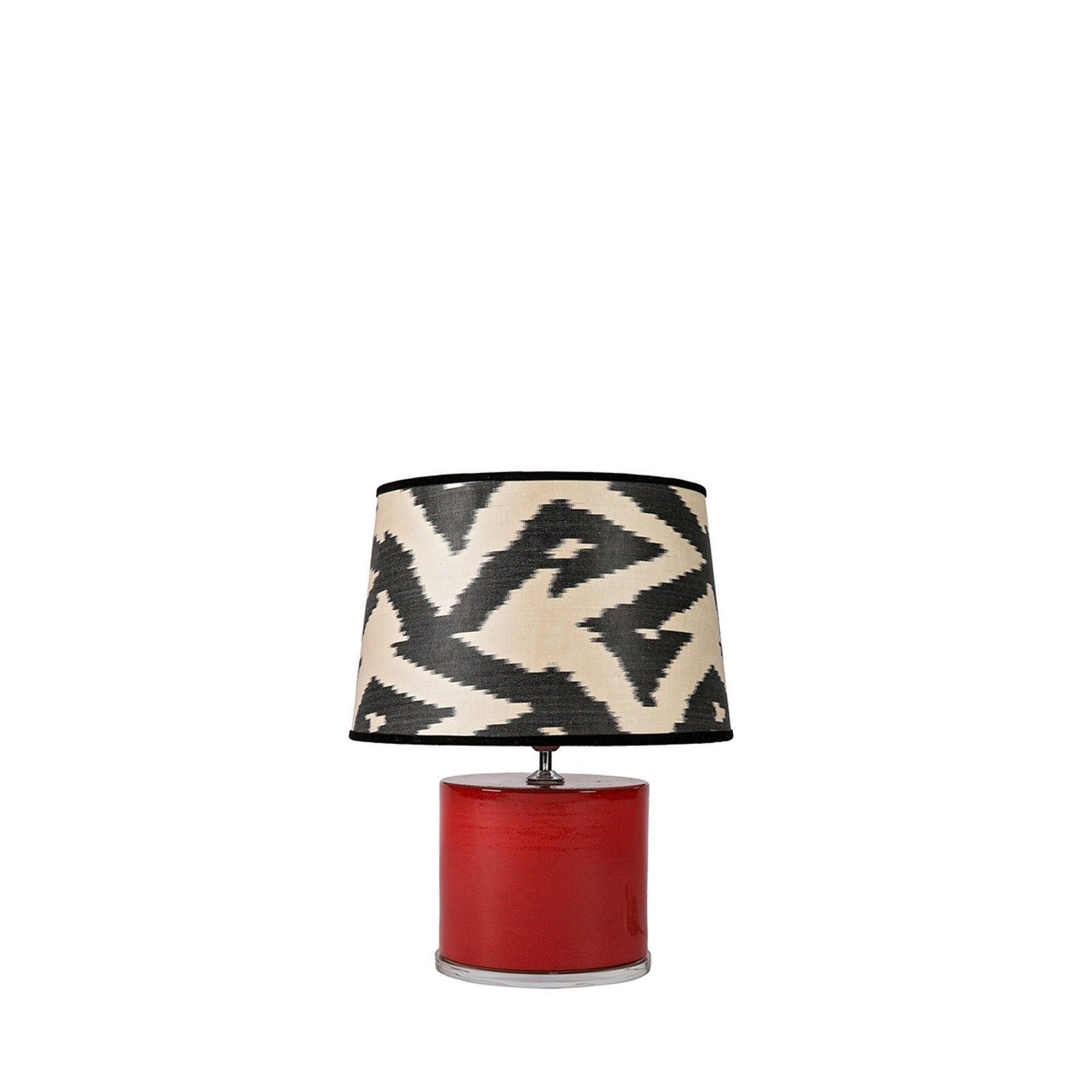 Table lamp with a black and white patterned shade and red base on a white background